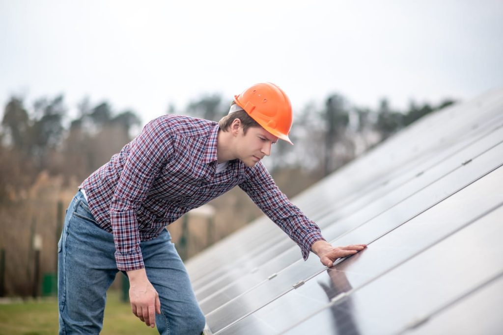A property damage inspector in a safety helmet examining a building’s exterior to document hidden damage for a supplement on a closed insurance claim.