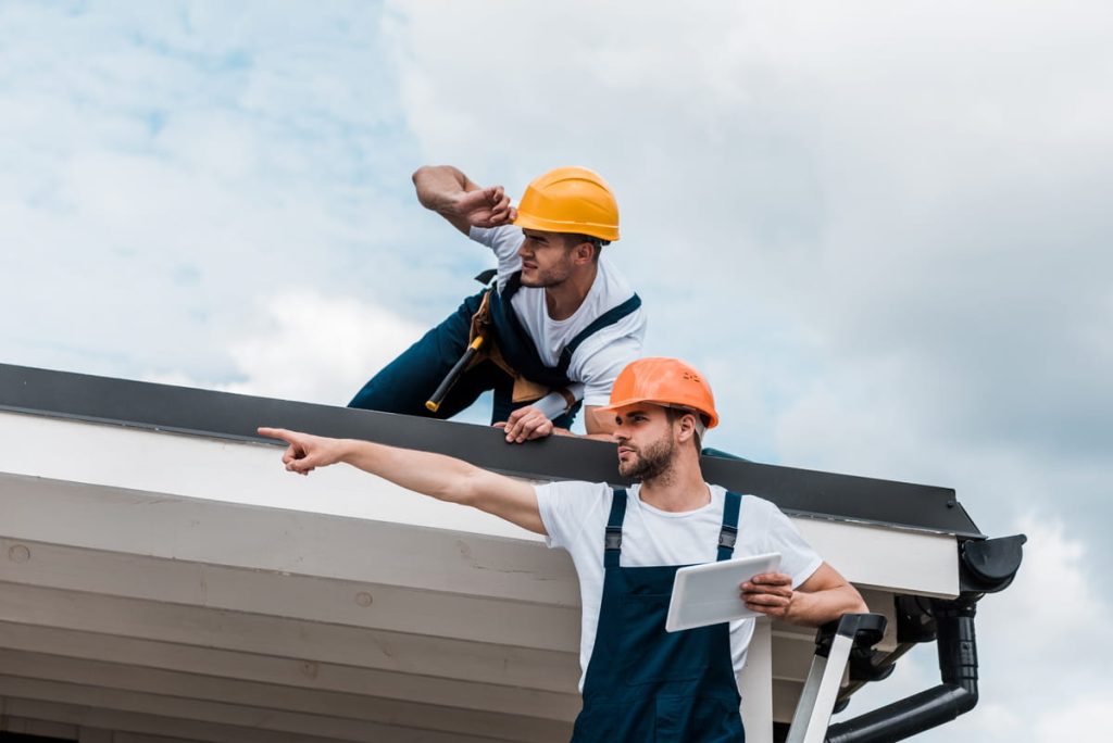 Two roofing contractors inspecting roof damage during an insurance claim assessment.